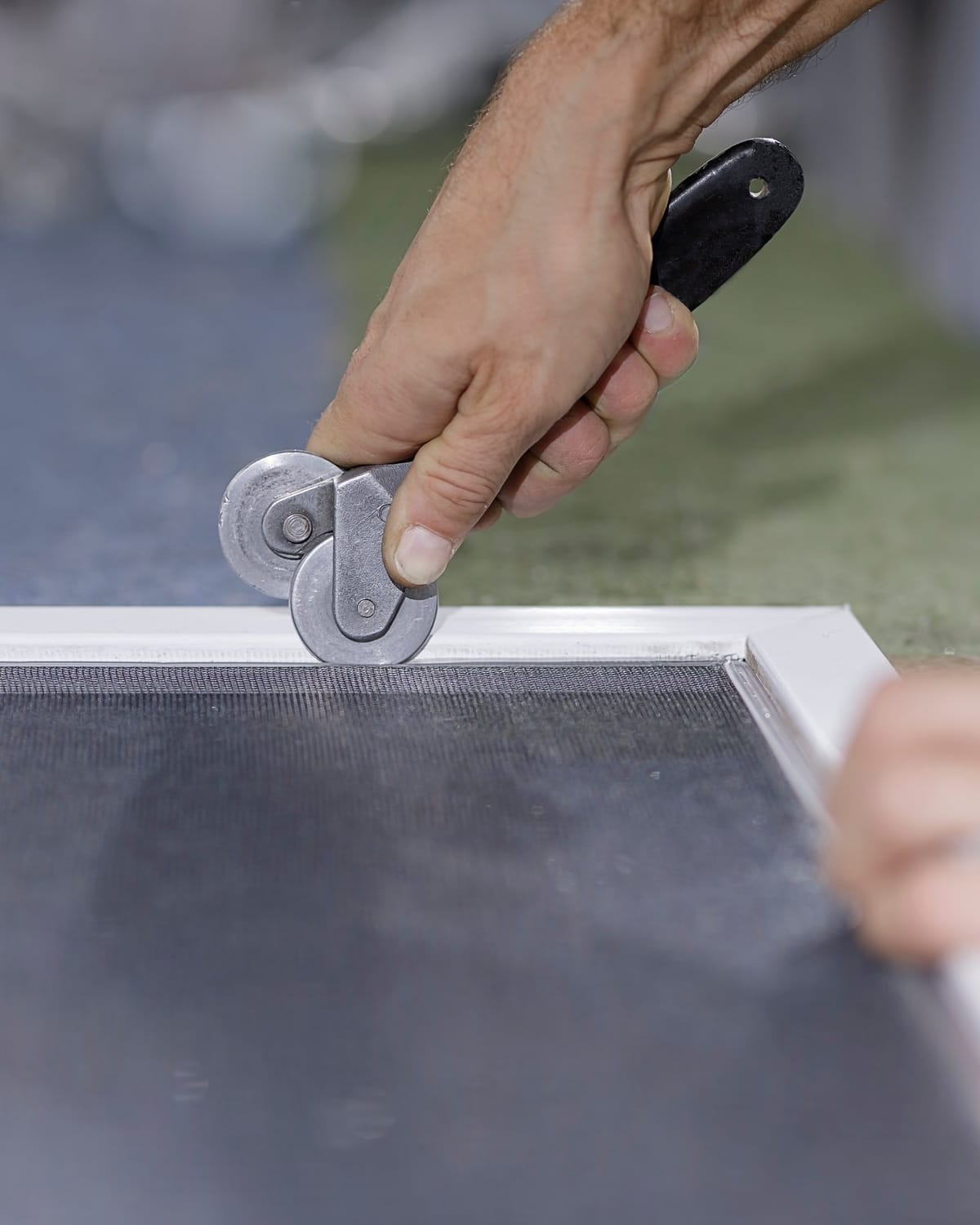 Rolling fresh spline into a screen frame with a spline roller